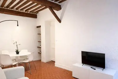 a living room with a tv on a white wall at Charme du Vieux-Nice - cocon lumineux à 100 m de la mer in Nice