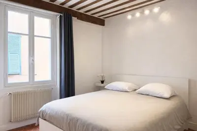 a bedroom with a bed with two pillows and a window at Charme du Vieux-Nice - cocon lumineux à 100 m de la mer in Nice