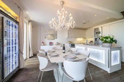a kitchen with a white table and chairs and a chandelier at Villa Belle Epoque, sea view, pool & hammam in Èze