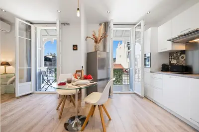 a kitchen with white walls and a table and chairs at BelAzur - L'art de vivre au cœur de Nice in Nice