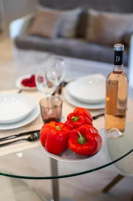 a plate of tomatoes on a glass table with a bottle of wine at BelAzur - L'art de vivre au cœur de Nice in Nice