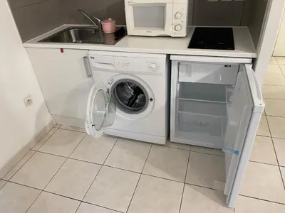 a kitchen with a washing machine and a microwave at Palais Des Domes Adagio Aparthotel in Nice