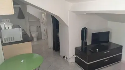 a living room with a tv on a dresser and a room with a staircase at Charmant logement central in Nice