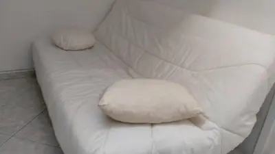 a white couch with two pillows on it at Charmant logement central in Nice