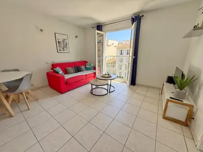 a living room with a red couch and a table at 4-person apartment - Air conditioning and Pool in Nice