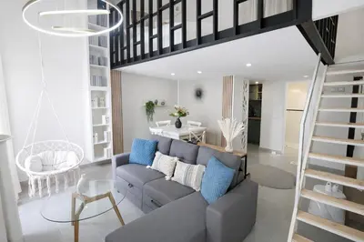 a living room with a gray couch and a staircase at Azur Carré d'or Duplex 6 pers 2 min de la mer in Nice