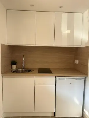 a kitchen with white cabinets and a sink and a refrigerator at Studio - Nice Palais des Expositions in Nice