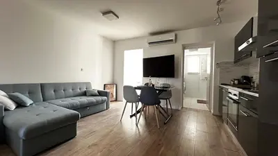 a living room with a couch and a table and a kitchen at Appartement elegant a Nice in Nice