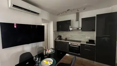 a kitchen with black cabinets and a table and a television at Appartement elegant a Nice in Nice
