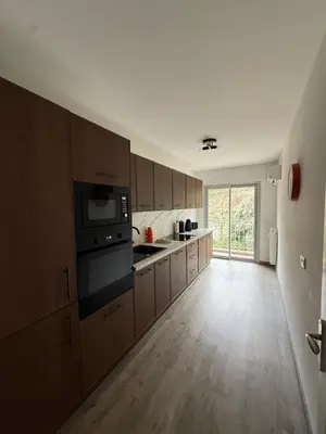 a kitchen with wooden cabinets and a large window at Appartement 3p proche mer in Nice