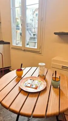 a wooden table with a plate and bowls on it at Grand studio cosy au cœur du Vieux-Nice in Nice