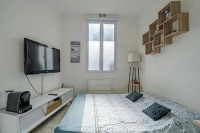 a white bedroom with a bed and a flat screen tv at Charmant studio cosy - Nice Est in Nice