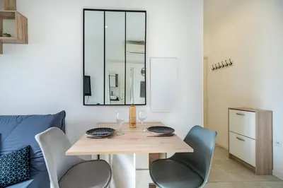 a dining room with a table with chairs and a mirror at Charmant studio cosy - Nice Est in Nice