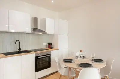 a kitchen with white cabinets and a table and chairs at Élégant 2 pièces Niçois - Carré d'Or - Centre Ville - Mer à 2 min in Nice