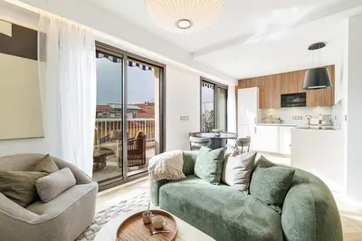 a living room with a green couch and a kitchen at Appartement Mamabaldi in Nice