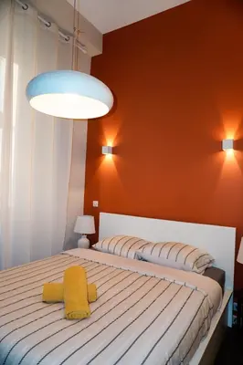 two beds in a bedroom with an orange wall at La Verrière du Vieux Nice in Nice