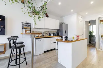 a kitchen with white cabinets and a bar with stools at MY CASA - EMMANUEL - Cozy apartment with Port view in Nice