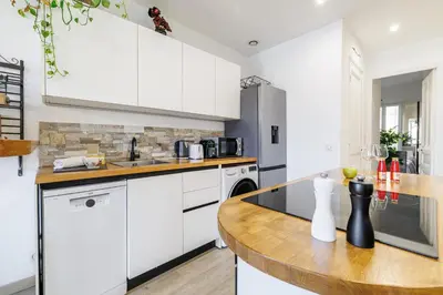 a kitchen with white cabinets and a wooden counter top at MY CASA - EMMANUEL - Cozy apartment with Port view in Nice