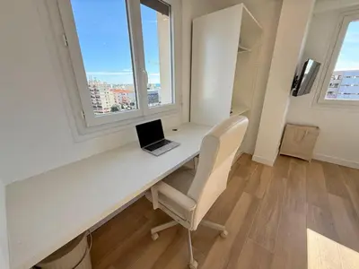 a laptop computer sitting on a desk in a room with windows at Nice Ouest Chambres Privees Modernes TV Wifi Bureau in Nice