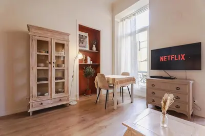 a living room with a television and a dining room table at L'Écrin de la Piétonne in Nice