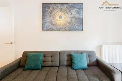 a couch with two blue pillows in a living room at Nice 2 pièces proche centre in Nice