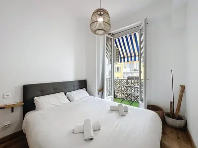 a bedroom with a large white bed and a balcony at Spacieux 3p Nice Riquier terrasse clim parking in Nice