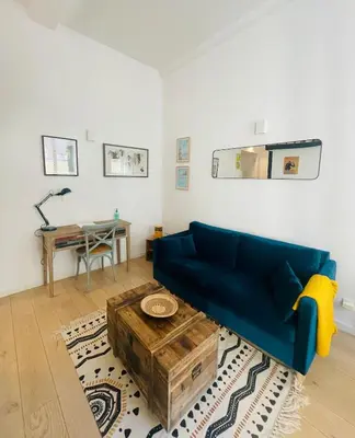a living room with a blue couch and a table at Bright modern studio, Nice Port, walk to tram and beach! in Nice
