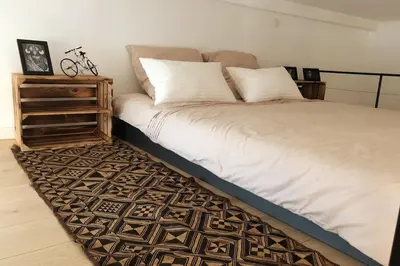 a bed with white sheets and pillows on a rug at Bright modern studio, Nice Port, walk to tram and beach! in Nice