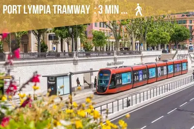 a red train on the tracks in a city at Bright modern studio, Nice Port, walk to tram and beach! in Nice