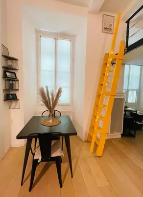 a dining room with a table and a yellow ladder at Bright modern studio, Nice Port, walk to tram and beach! in Nice