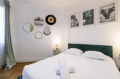 a bedroom with a large white bed and some pictures on the wall at Large 2 Bdr City Center close to Train Station in Nice