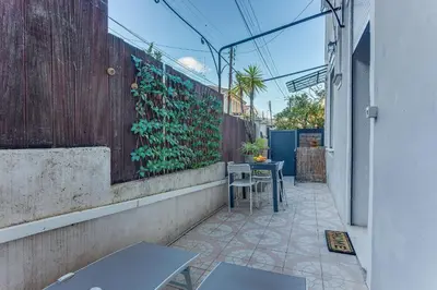 a patio with tables and chairs and a wall with plants at LE CYRNOS AP4499 By Riviera Holiday Homes in Nice