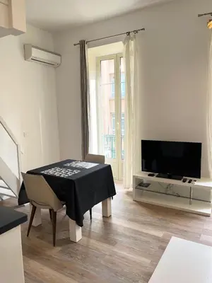 a white living room with a table and a television at Studio Mezzanine - Clim Balcon - centre ville in Nice