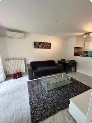 a living room with a black couch and a glass table at 2 pièces RDJ Proche Mer in Nice