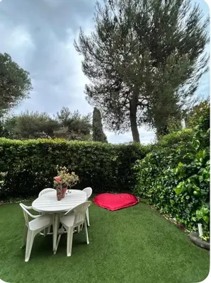 a table and chairs on the grass with a red blanket at 2 pièces RDJ Proche Mer in Nice