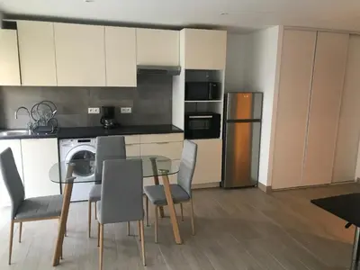 a kitchen with a table and chairs and a refrigerator at Studio Libération Piscine centre ville Nice in Nice