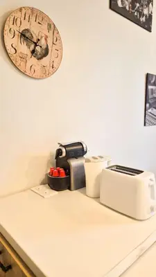 a counter with a toaster and a clock on the wall at Joli T3 moderne avec terrasse & climatisation in Nice