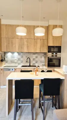 a kitchen with a large white island with two chairs at Joli T3 moderne avec terrasse & climatisation in Nice