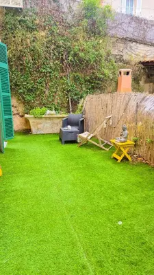 a backyard with a lawn with a couch and a table at Joli T3 moderne avec terrasse & climatisation in Nice