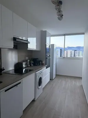 a kitchen with white cabinets and a washer and dryer at Deux pièces moderne avec balcon & Vue dégagée in Nice