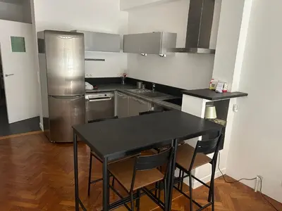 a kitchen with a black table and a refrigerator at Appart Centre ville à 2 min à pied de la mer in Nice