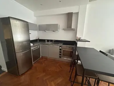 a kitchen with a stainless steel refrigerator and a table at Appart Centre ville à 2 min à pied de la mer in Nice