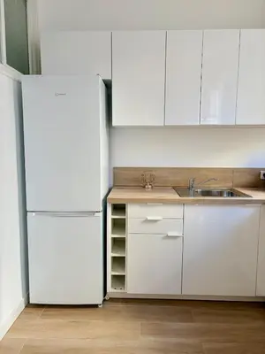 a kitchen with white cabinets and a refrigerator at Studio avec balcon - Centre-ville & plage à 2 min in Nice