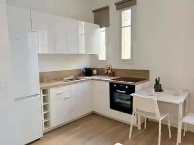 a kitchen with white cabinets and a small table at Studio avec balcon - Centre-ville & plage à 2 min in Nice