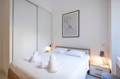a white bedroom with a large white bed with white pillows at The Apartment with the Garden Studio in Nice