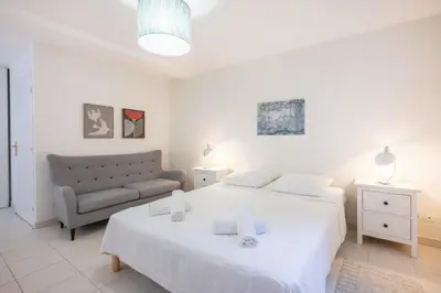 a white bedroom with a bed and a couch at The Apartment with the Garden Studio in Nice