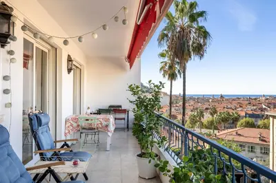 a balcony with a table and chairs and a view of the city at Azur Balcony Apartment Classic Charm with View in Nice