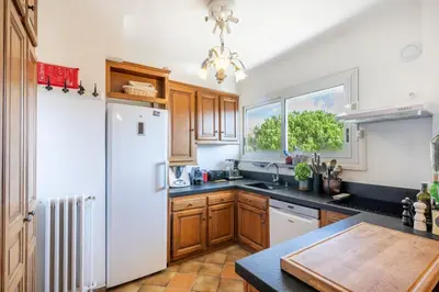 a kitchen with wooden cabinets and a white refrigerator at Azur Balcony Apartment Classic Charm with View in Nice