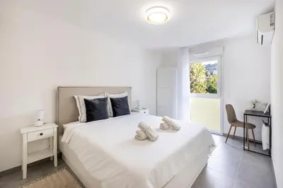 a white bedroom with a white bed with shoes on it at Appartement du Port with park view in Nice