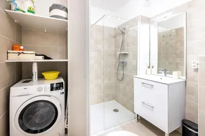 a bathroom with a washing machine and a shower at Appartement du Port with park view in Nice